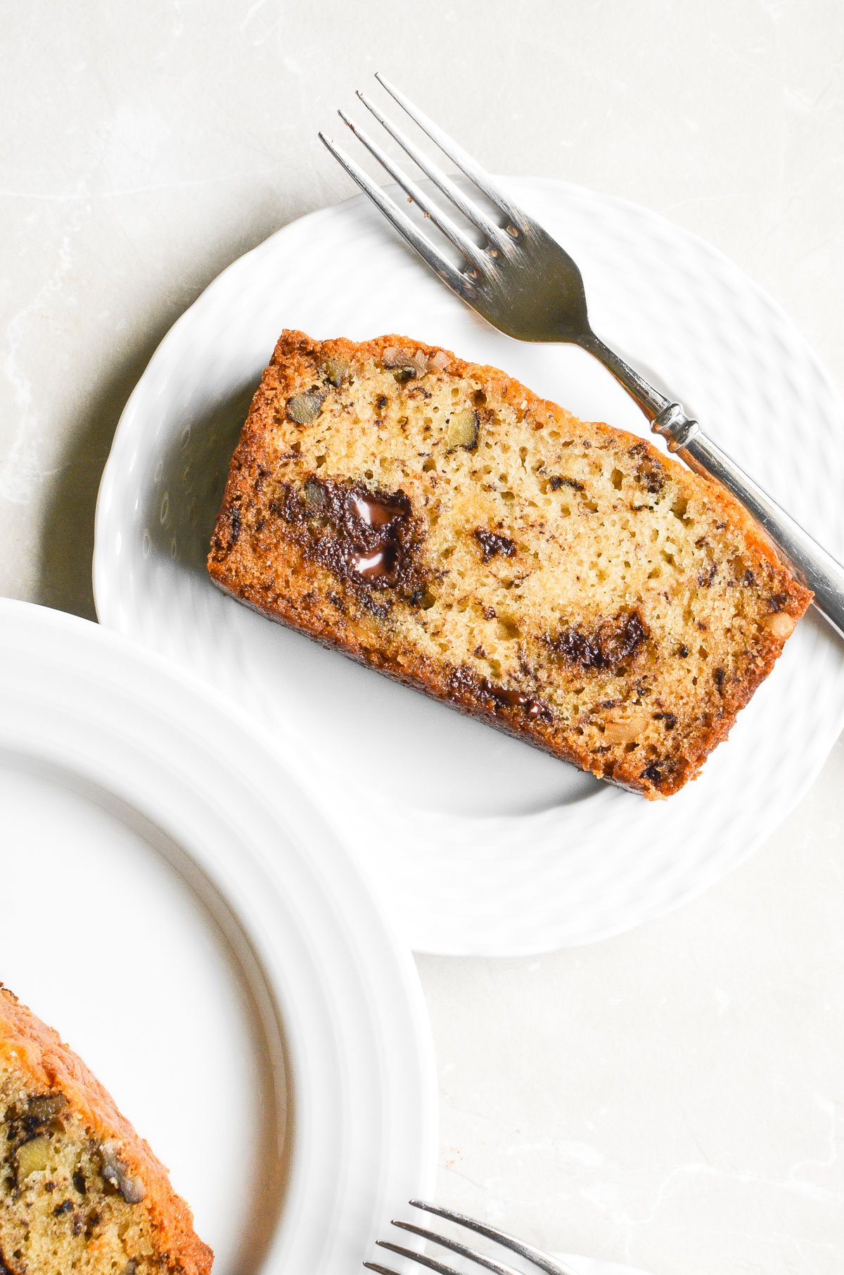 One Banana Banana Bread with Chocolate Chips and Walnuts ~ when there's just one banana left on the counter! #easy #recipe #bananas #bananabread #chocolatechipbananabread #quickbread #loafcake #bananacake #cake #breakfast #brunch A slice of banana bread on a plate with a fork.