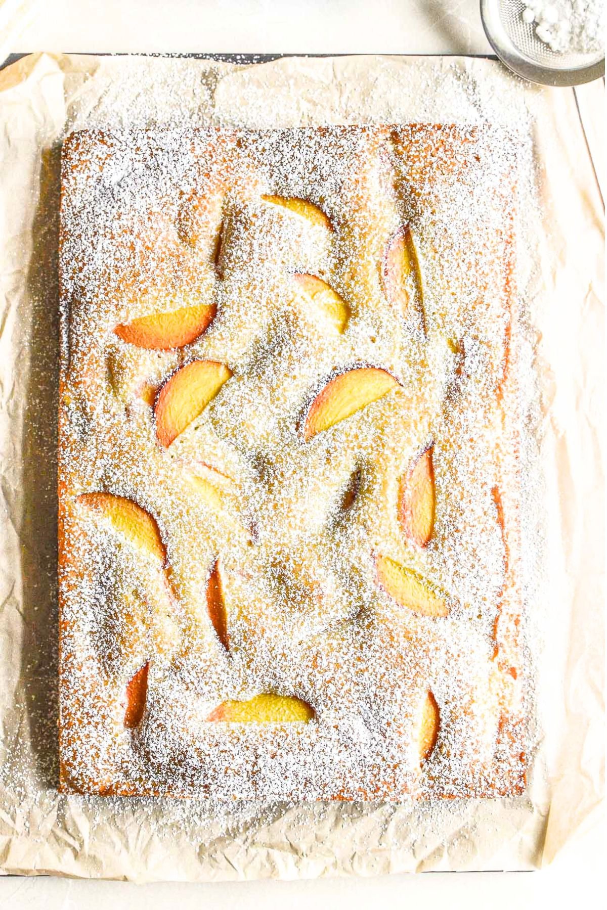 peach almond cake dusted with powdered sugar.