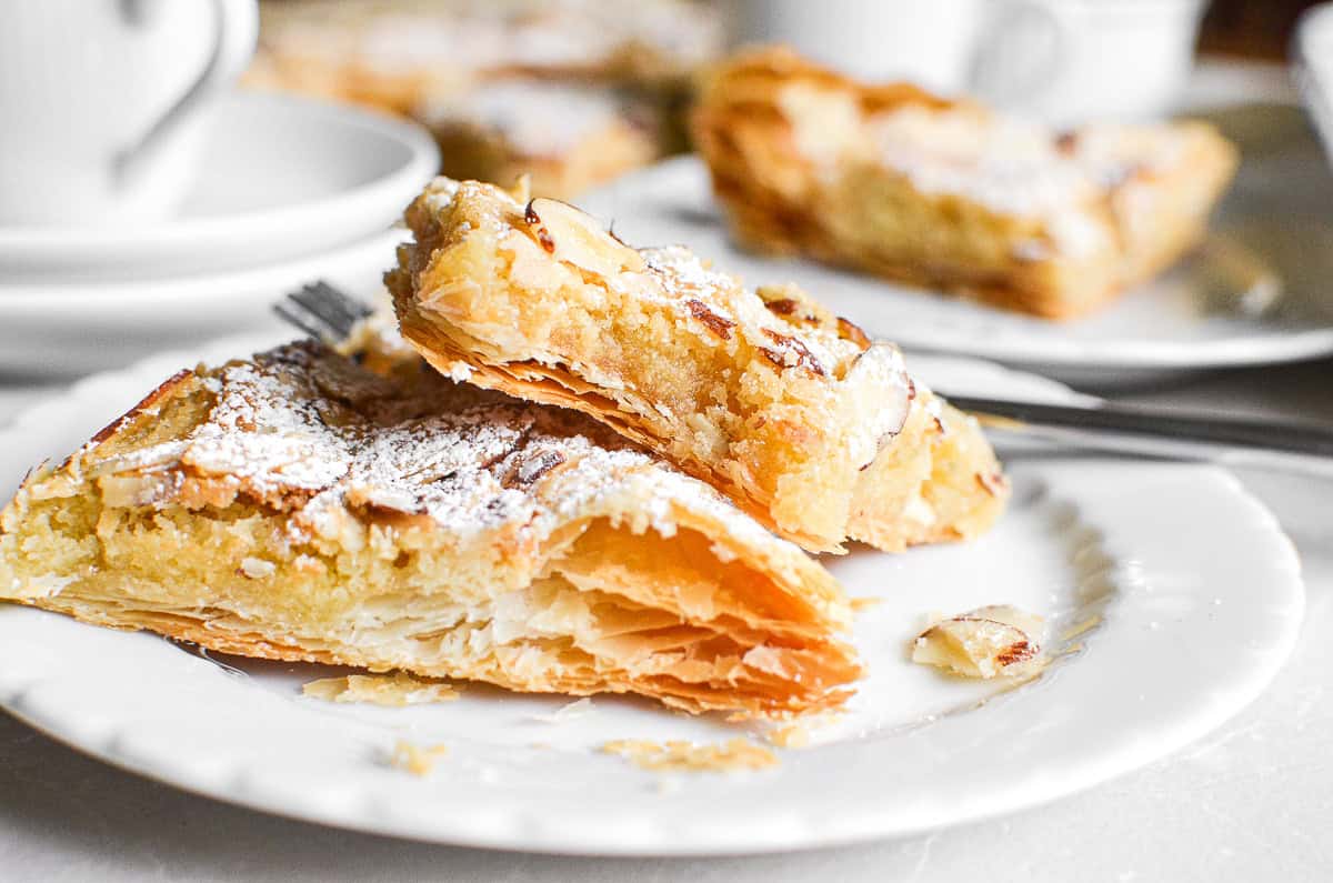 A piece of sheet pan almond croissant with a bite taken out.