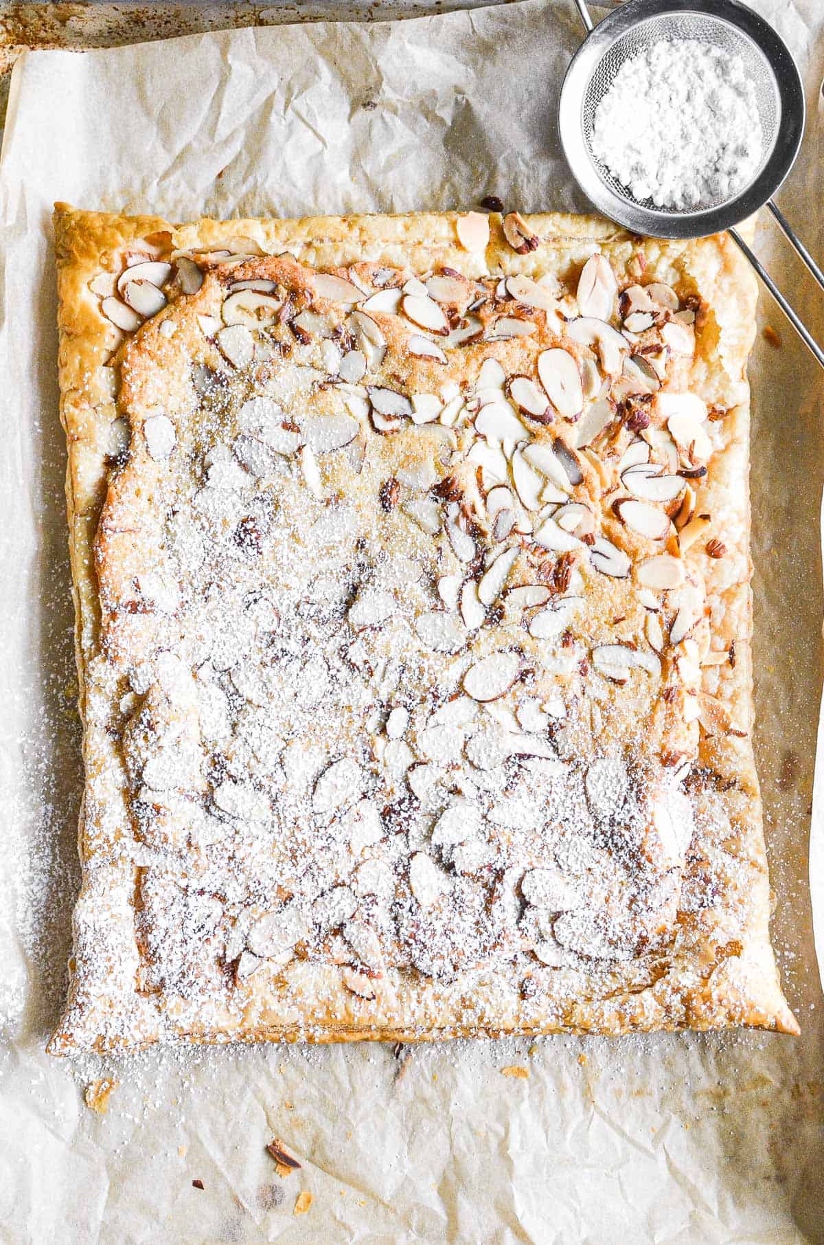 Sheet pan almond croissant with powdered sugar.