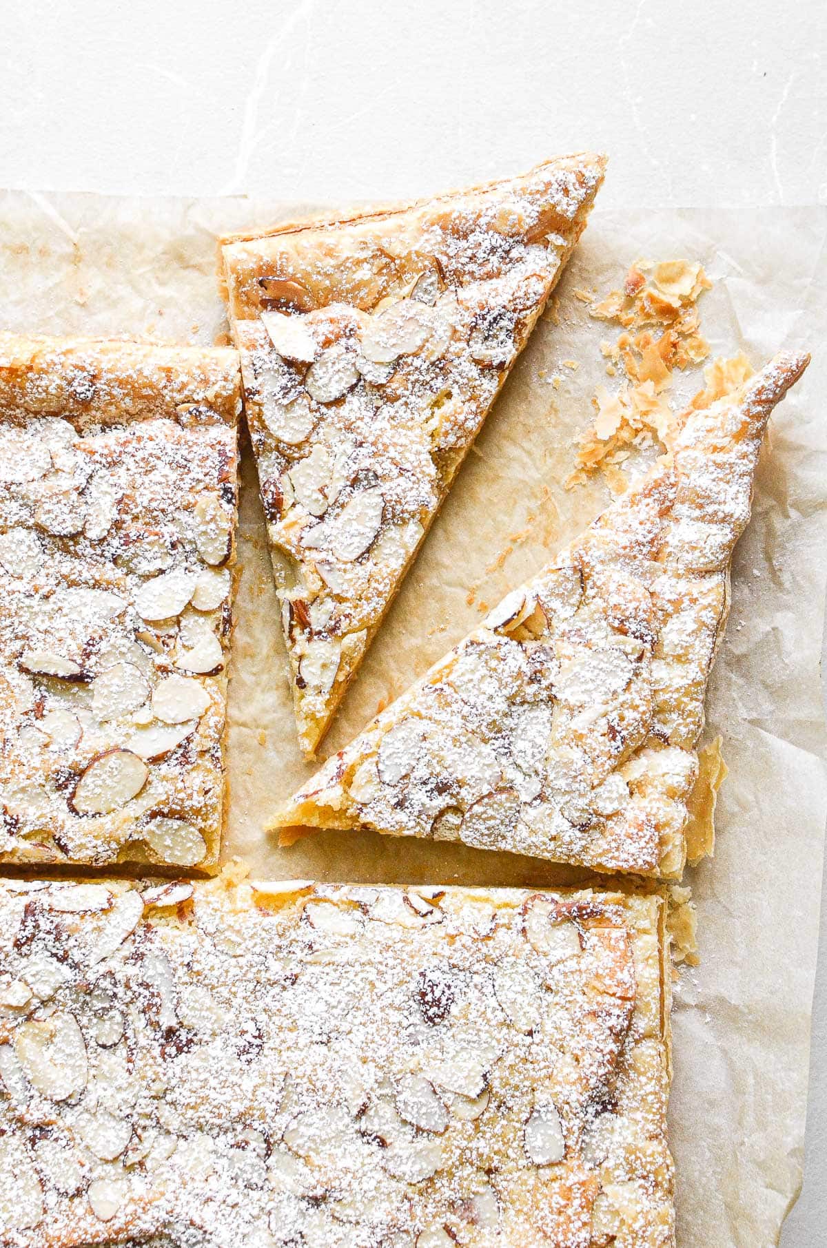 slicing sheet pan almond croissant into triangles.