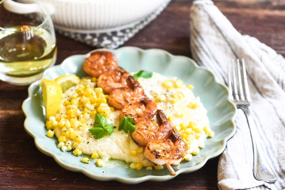 smoked cheddar shrimp and grits on a plate with corn. 