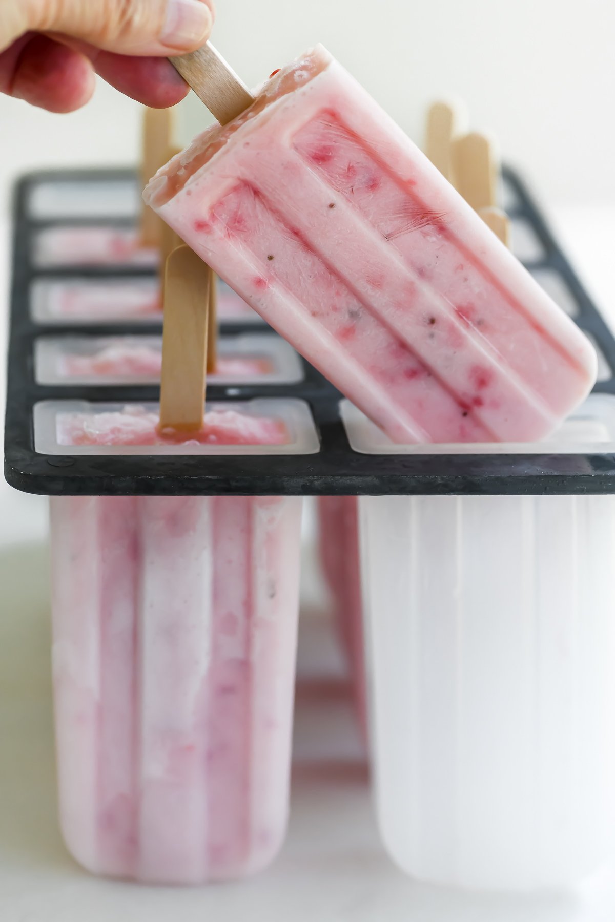 removing strawberry kefir popsicle from mold.