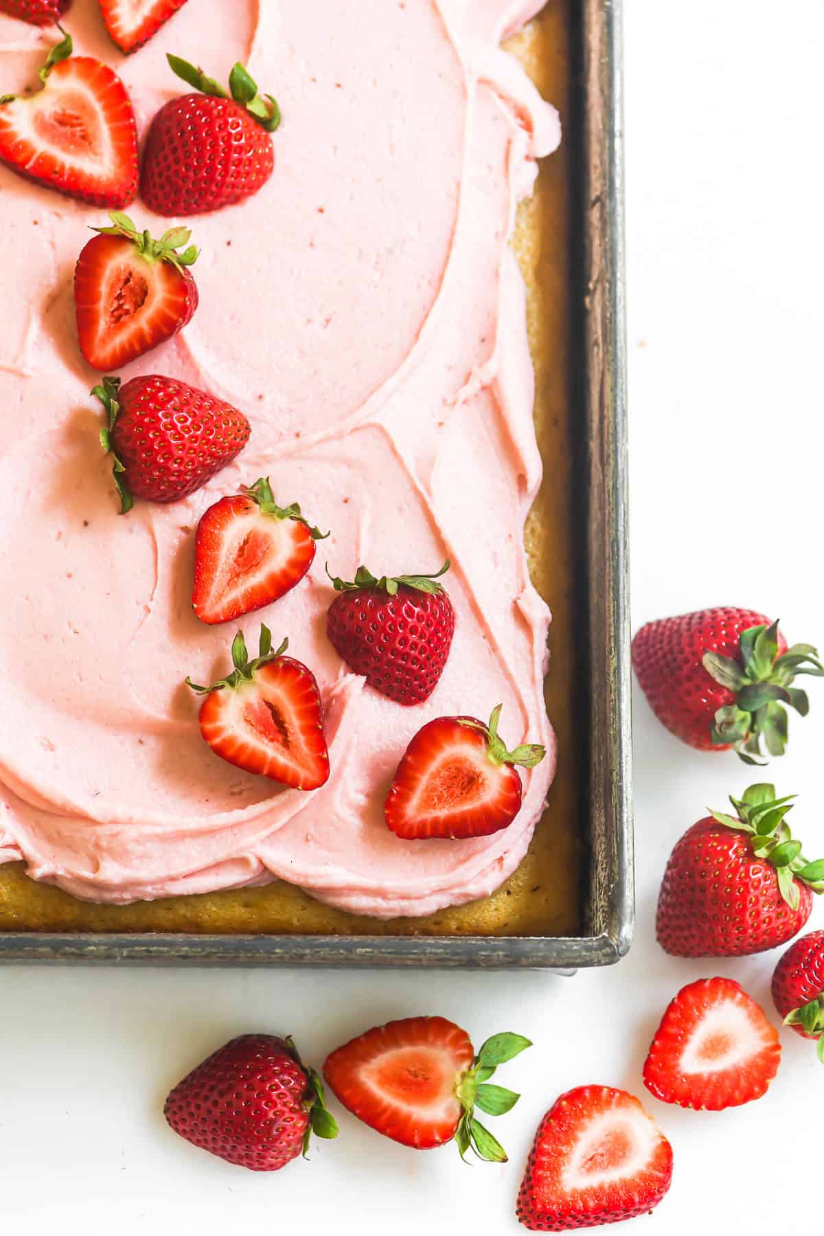 strawberry sheet cake decorated with sliced strawberries.