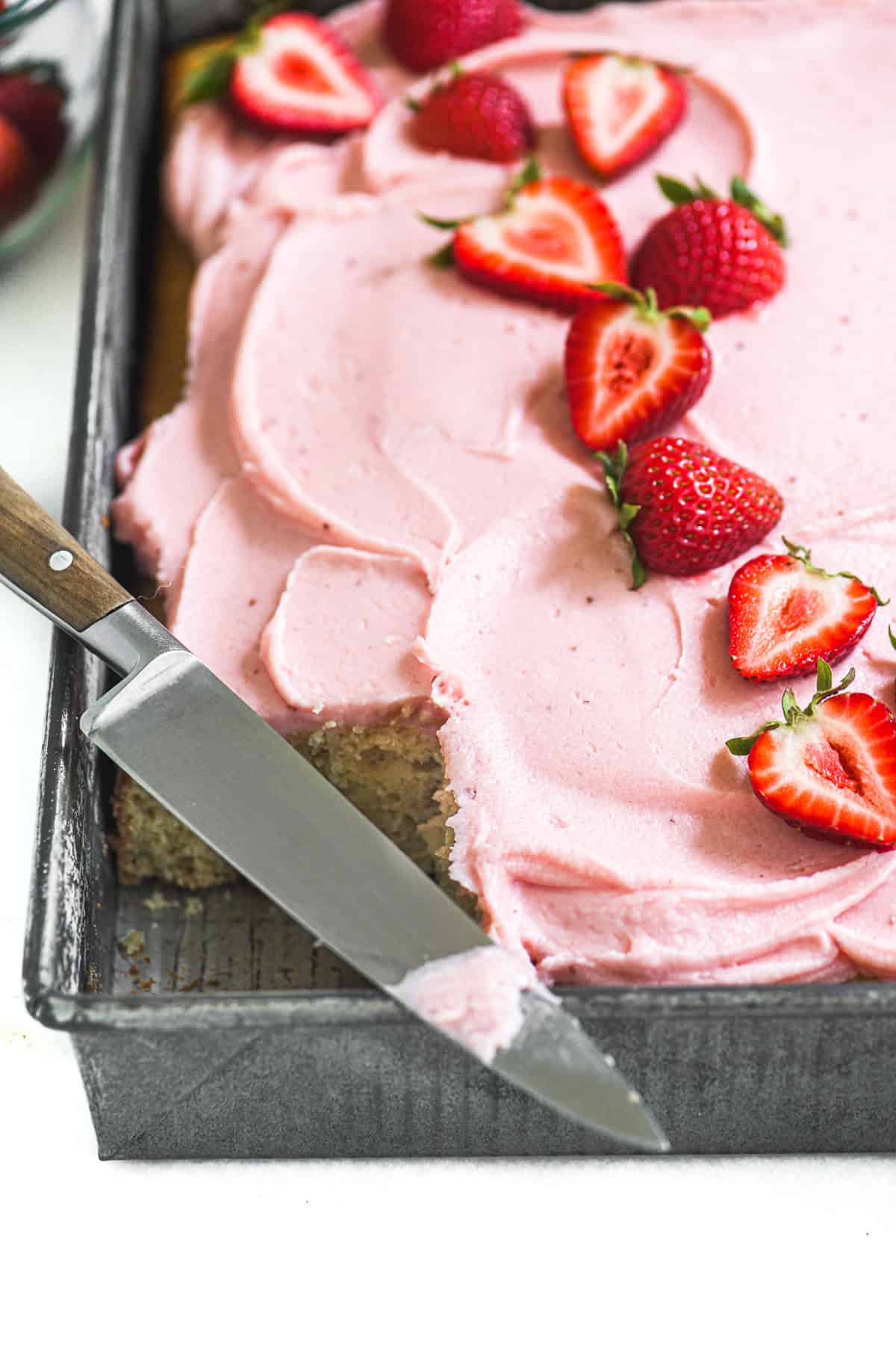 Strawberry sheet cake in a pan decorated with strawberries.