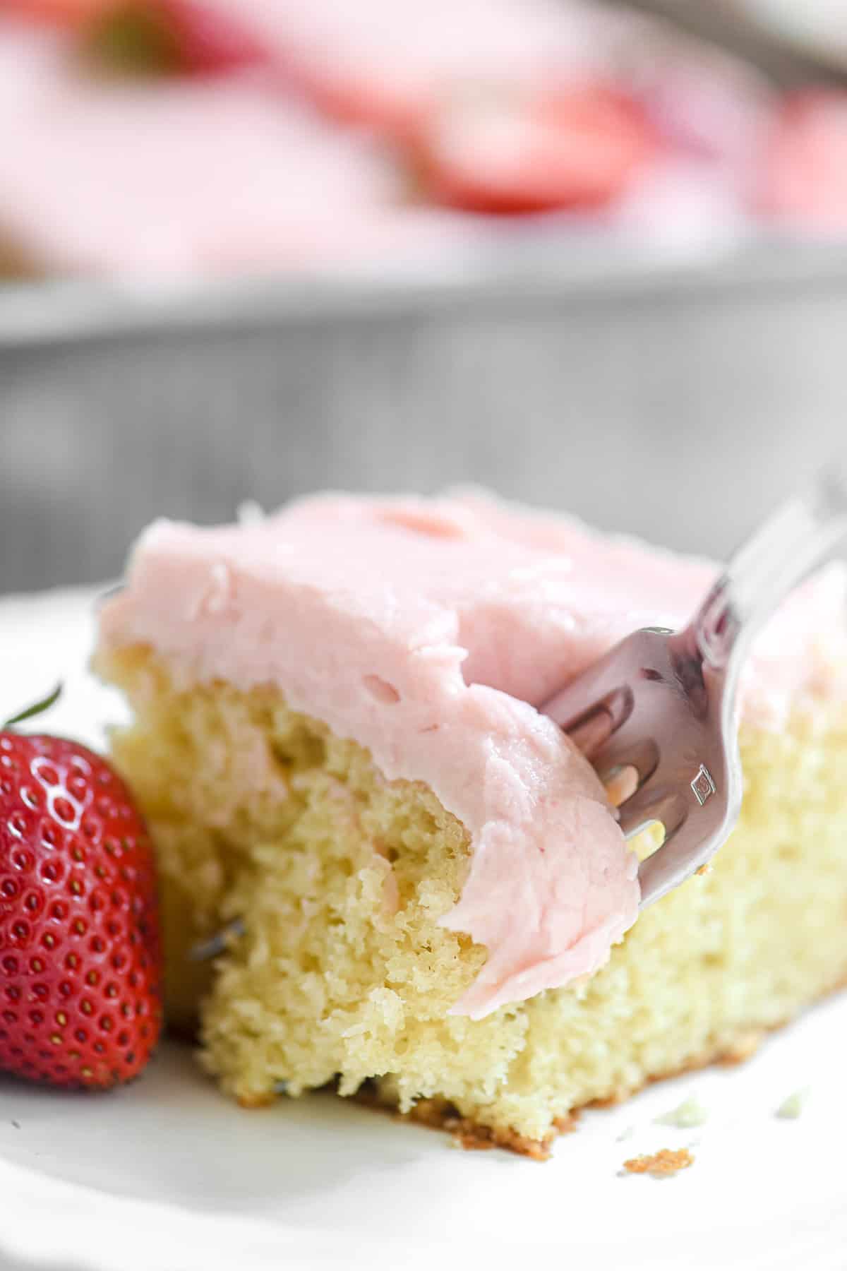 Taking a bite of a slice of strawberry sheet cake.
