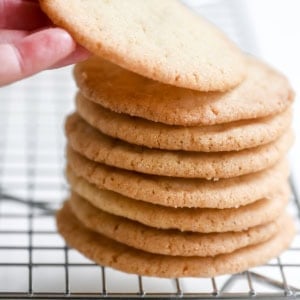 Taking a Thin and Crispy Sugar Cookie from a stack.