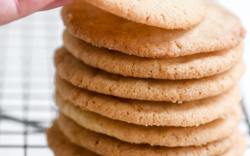 Taking a Thin and Crispy Sugar Cookie from a stack.