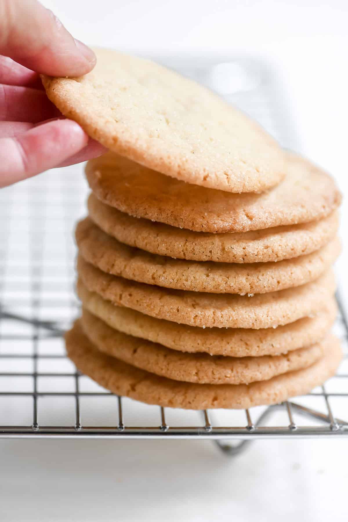 Taking a Thin and Crispy Sugar Cookie from a stack.