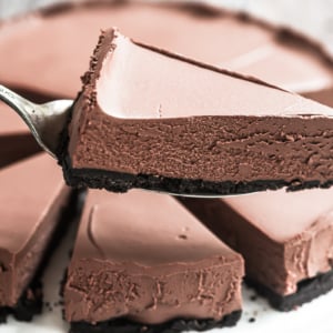 Taking a slice of no bake chocolate cheesecake with cake server.