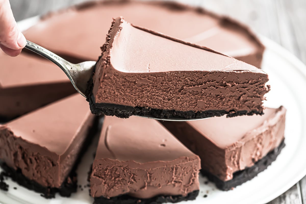 Taking a slice of no bake chocolate cheesecake with cake server.