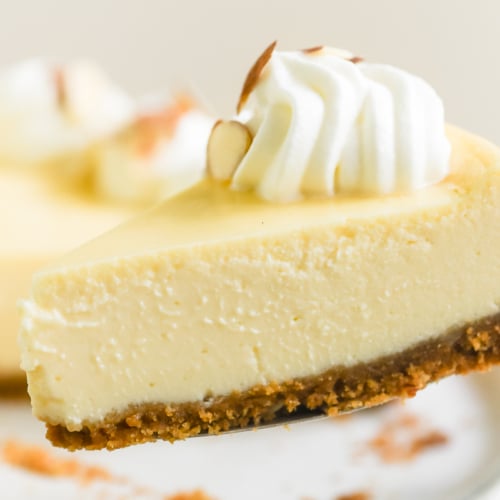 taking a slice of almond cheesecake with cake server.