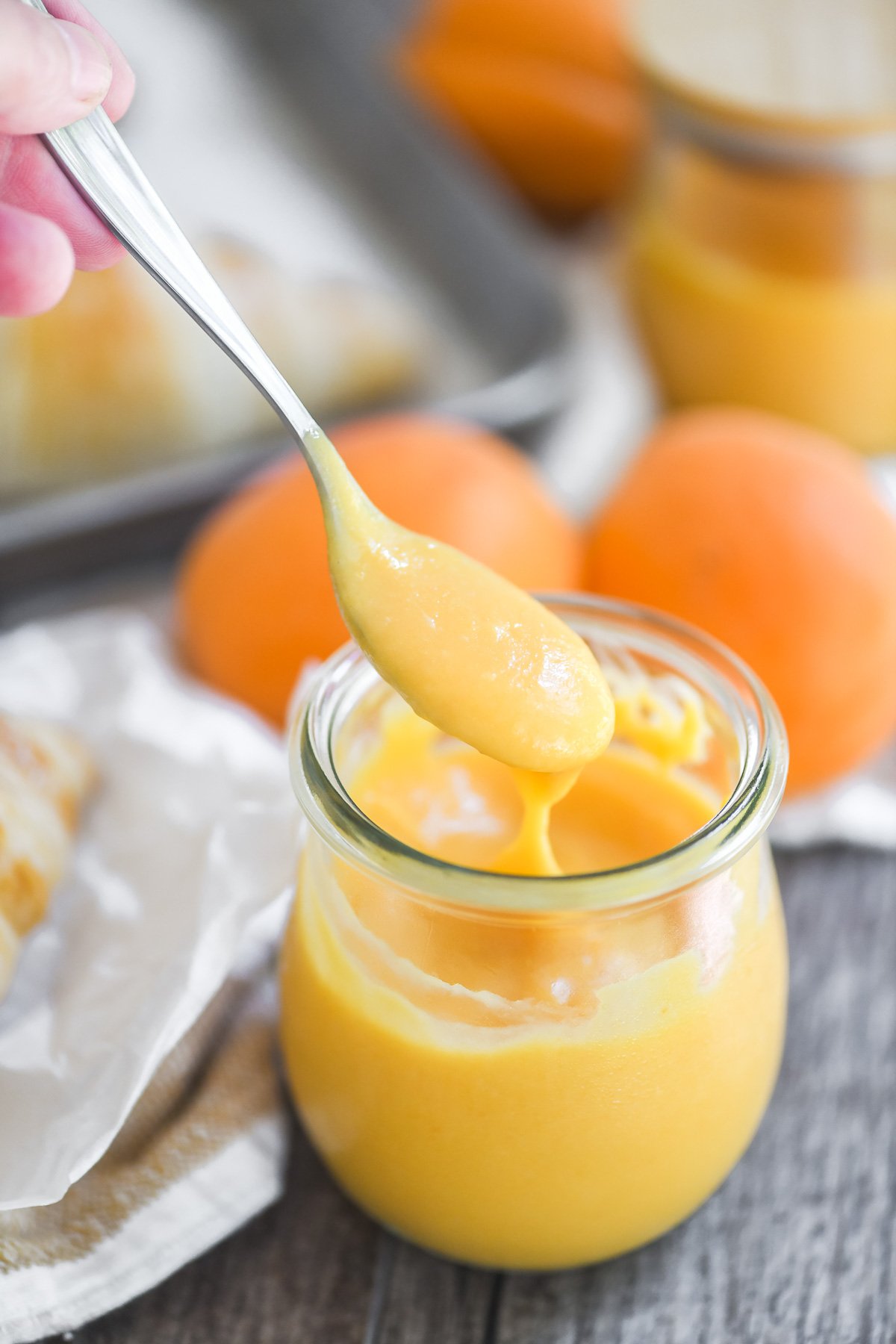 Dipping small spoon into a jar of apricot curd.