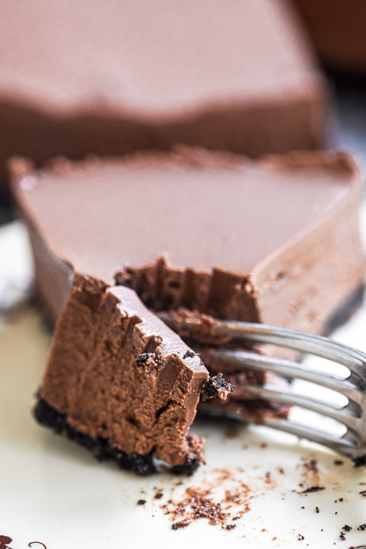 Taking a bite of a rich no bake chocolate cheesecake with a fork, close up view.