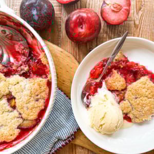 Plum cobbler being served with a large spoon.