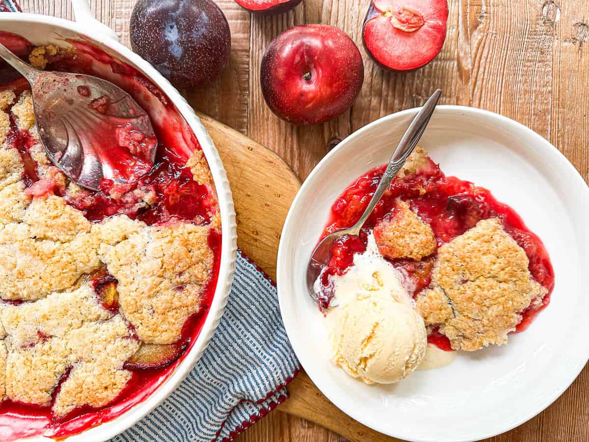 Plum cobbler being served with a large spoon.