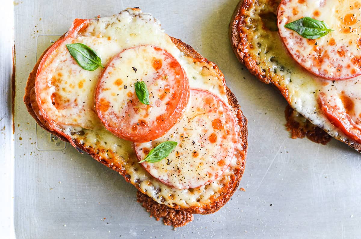 2 tomato melts topped with cheese and fresh basil.