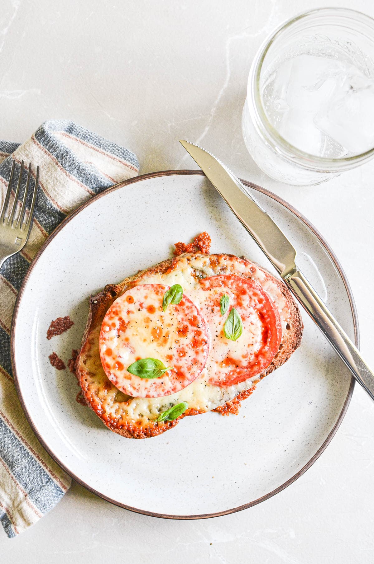 tomato melt on a white plate with knife.