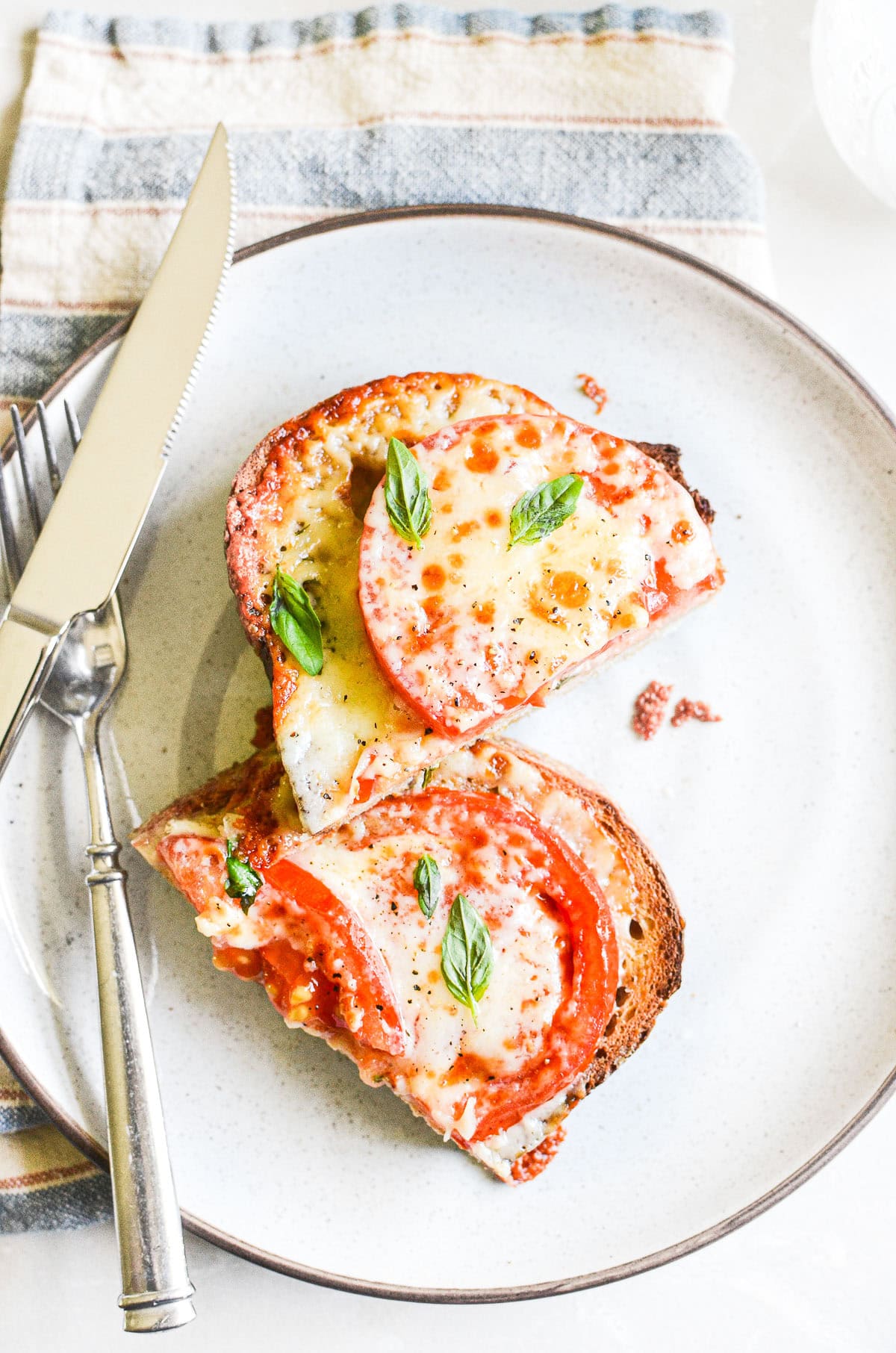 tomato melt sliced in half on a plate.
