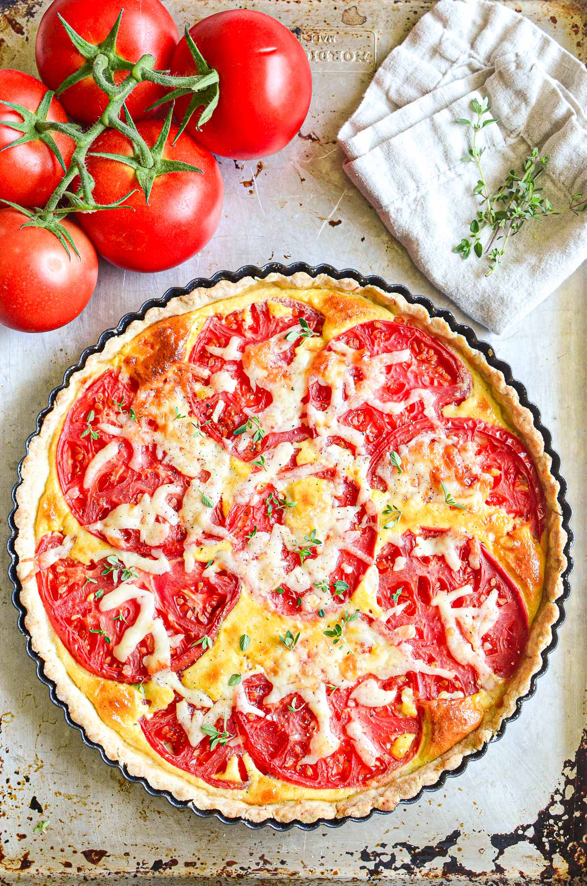 Tomato tart in a tart pan with fresh tomatoes.