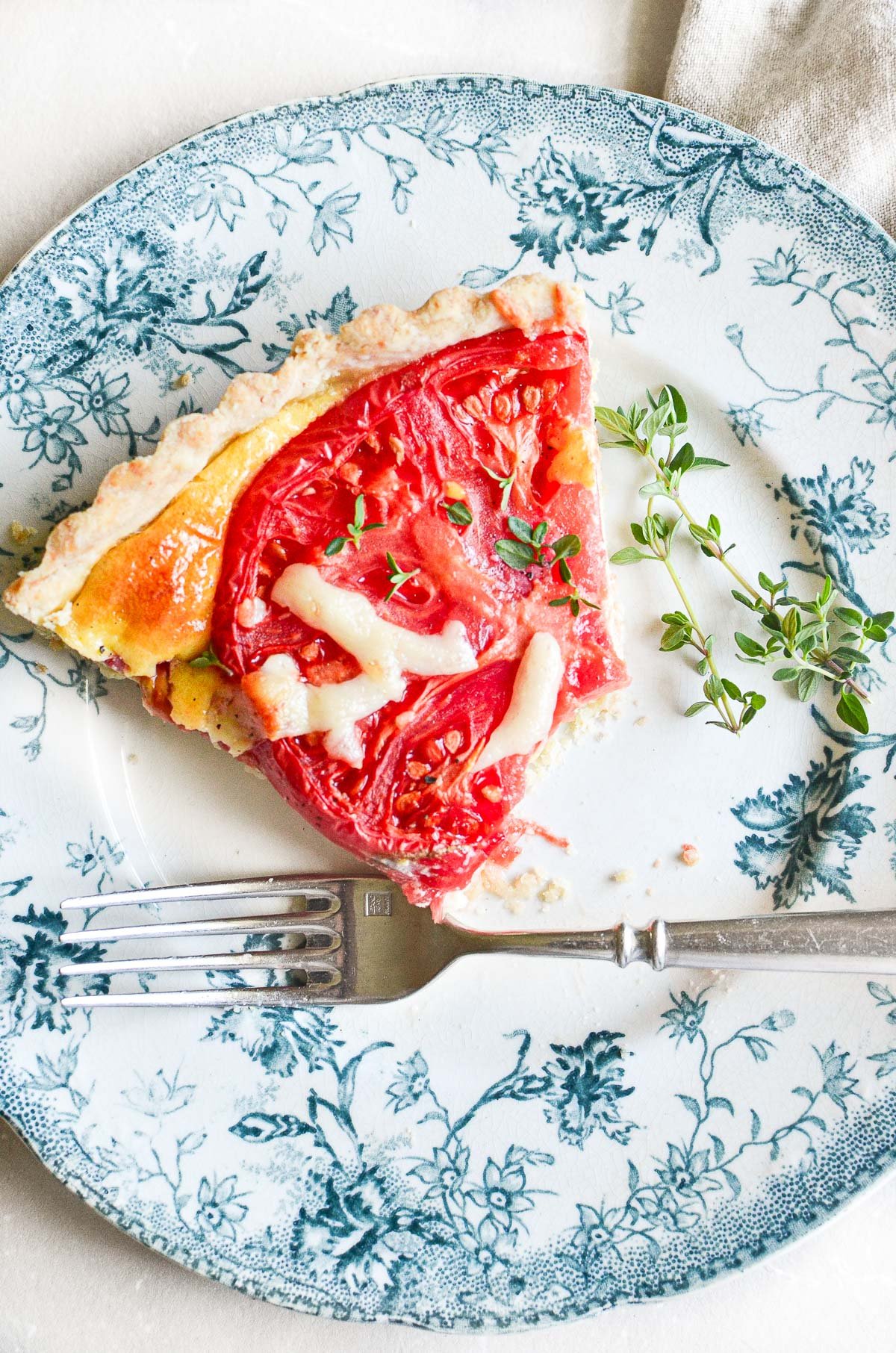A slice of tomato tart with bite taken.