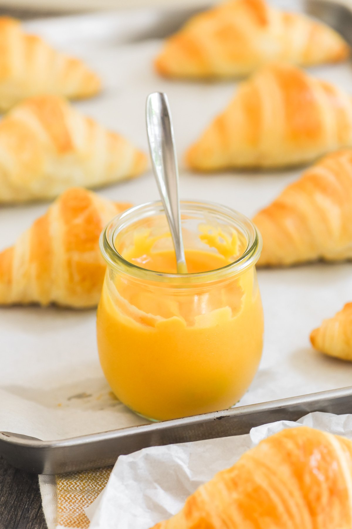 a small Weck jar of apricot curd on a tray with croissants.