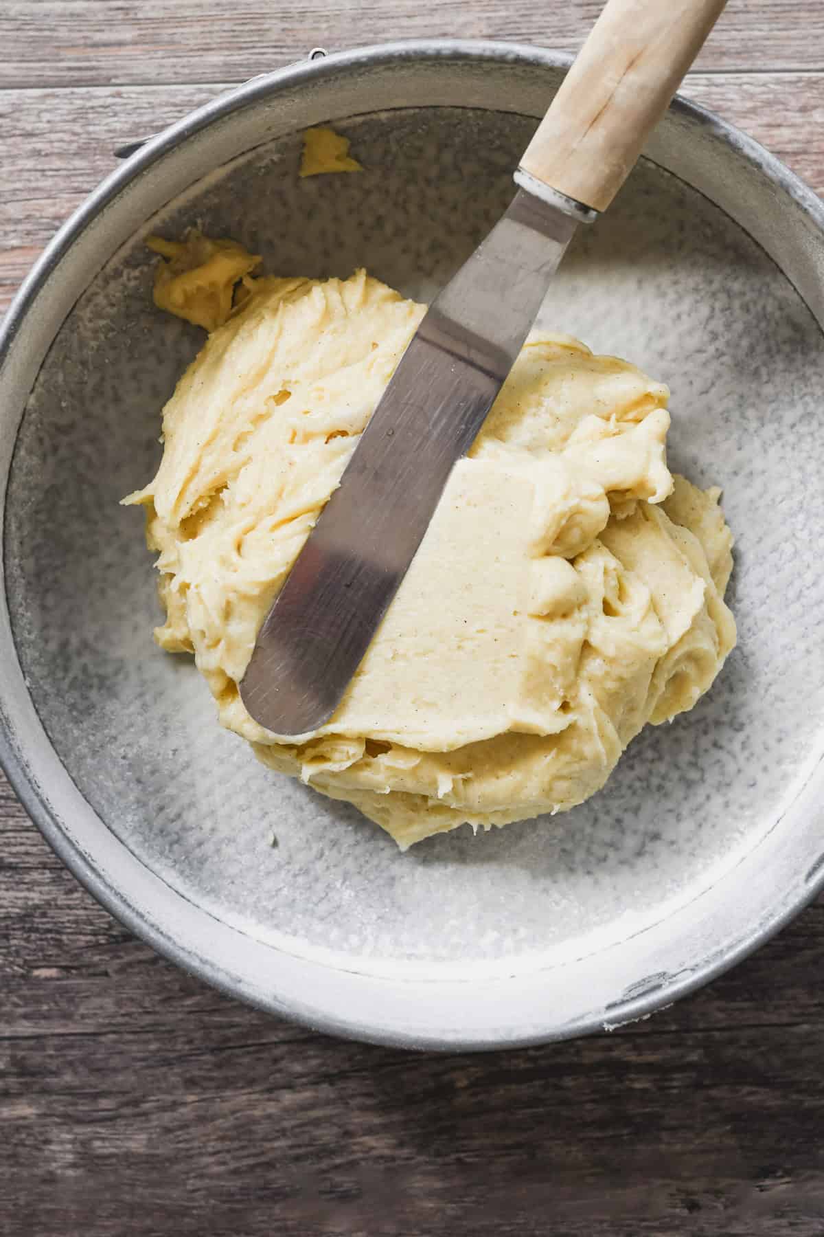 spreading cake batter in a springform pan for cardamom plum cake.