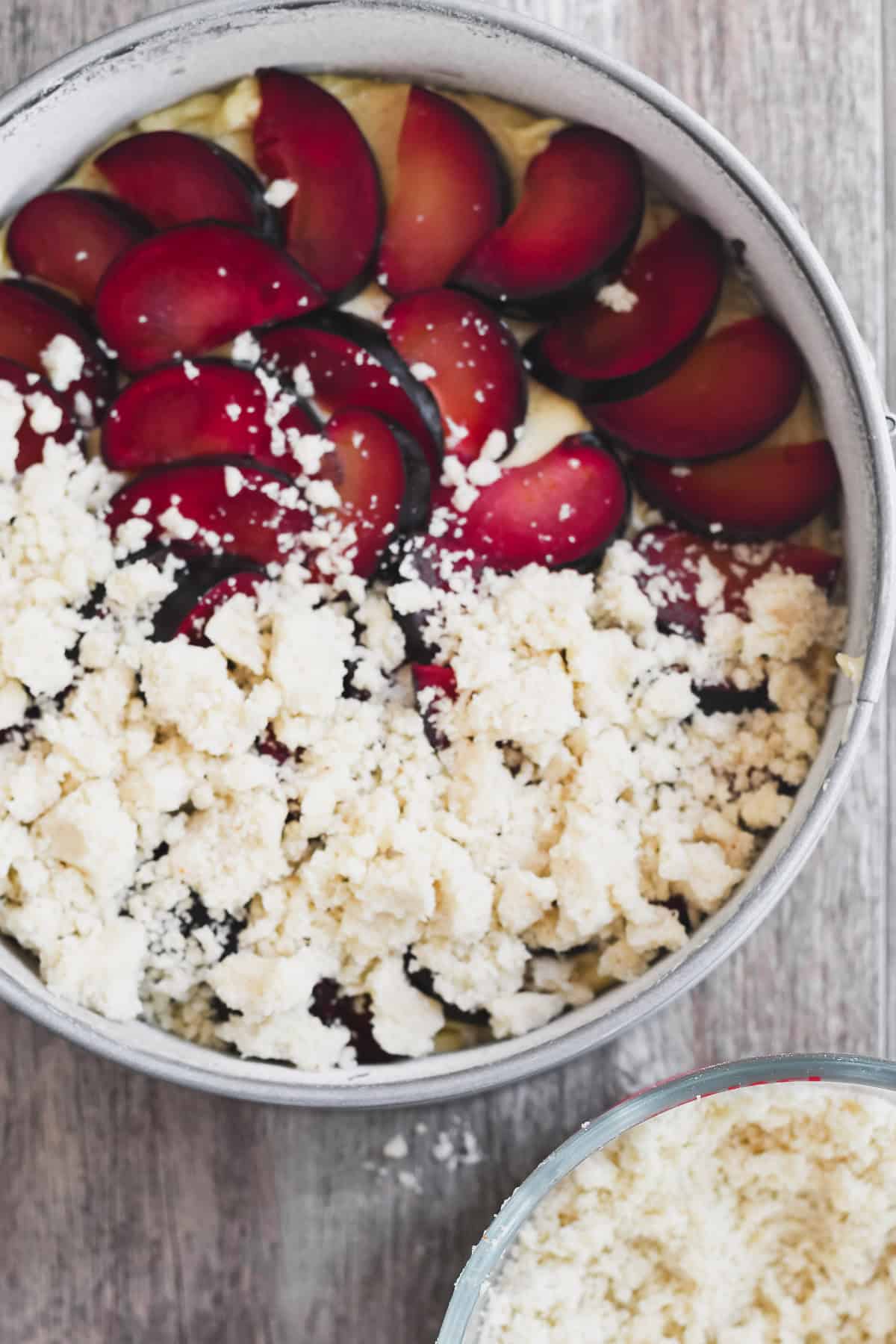 scattering crumble topping on a cardamom plum cake.