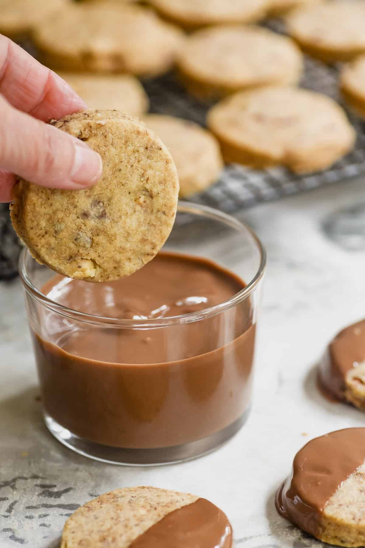 About to dip a coffee hazelnut shortbread cookie into melted milk chocolate.