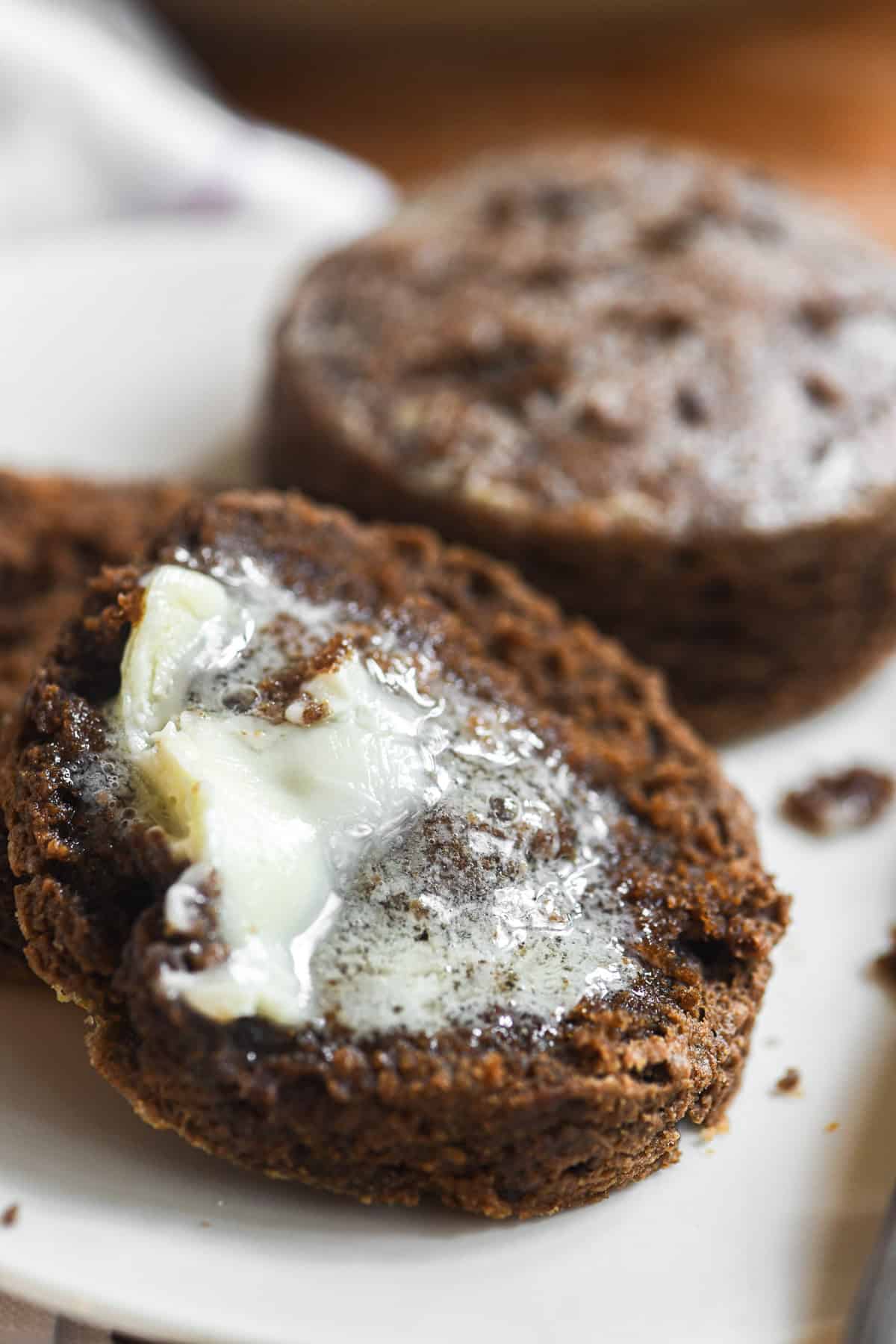Rich brown pumpernickel biscuit split with melting butter.
