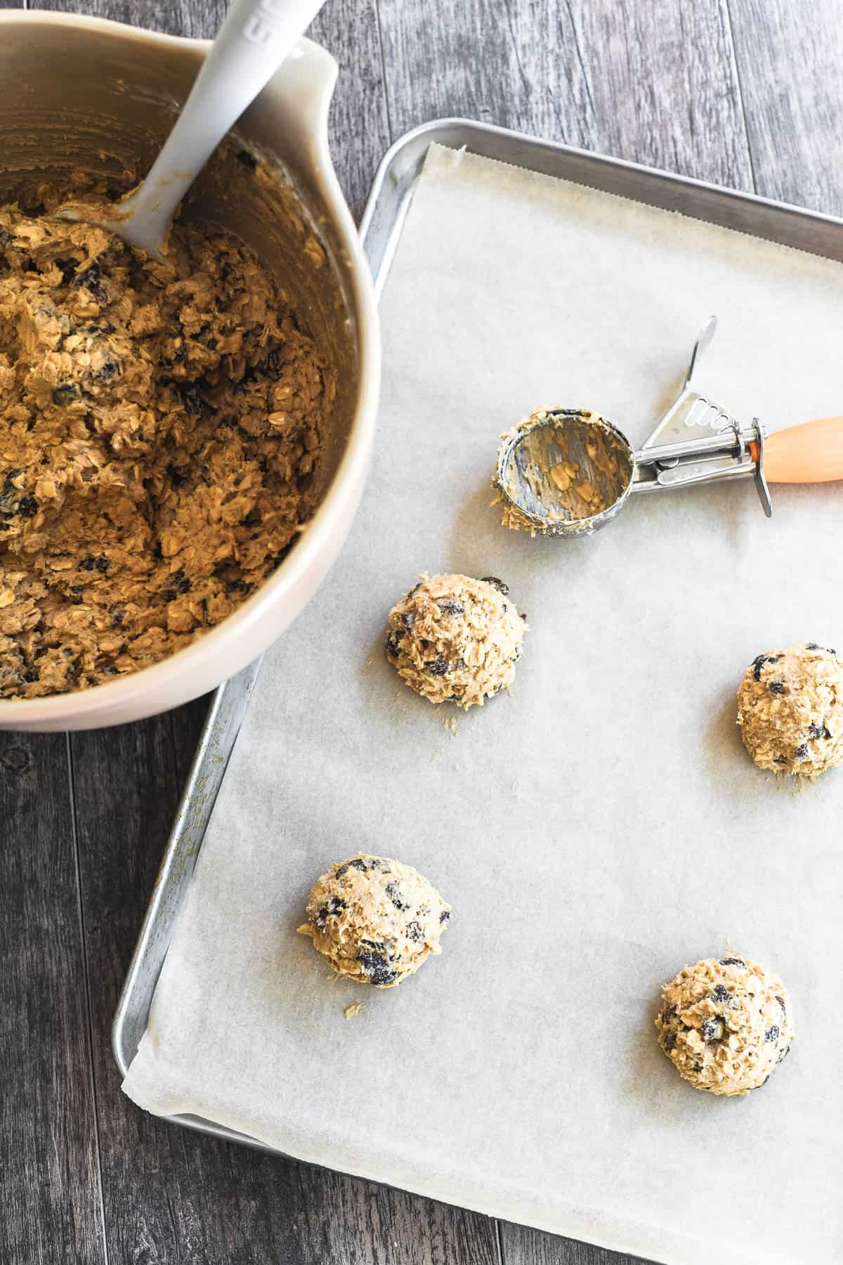 scooped out dough on a baking sheet for oatmeal raisin cookies