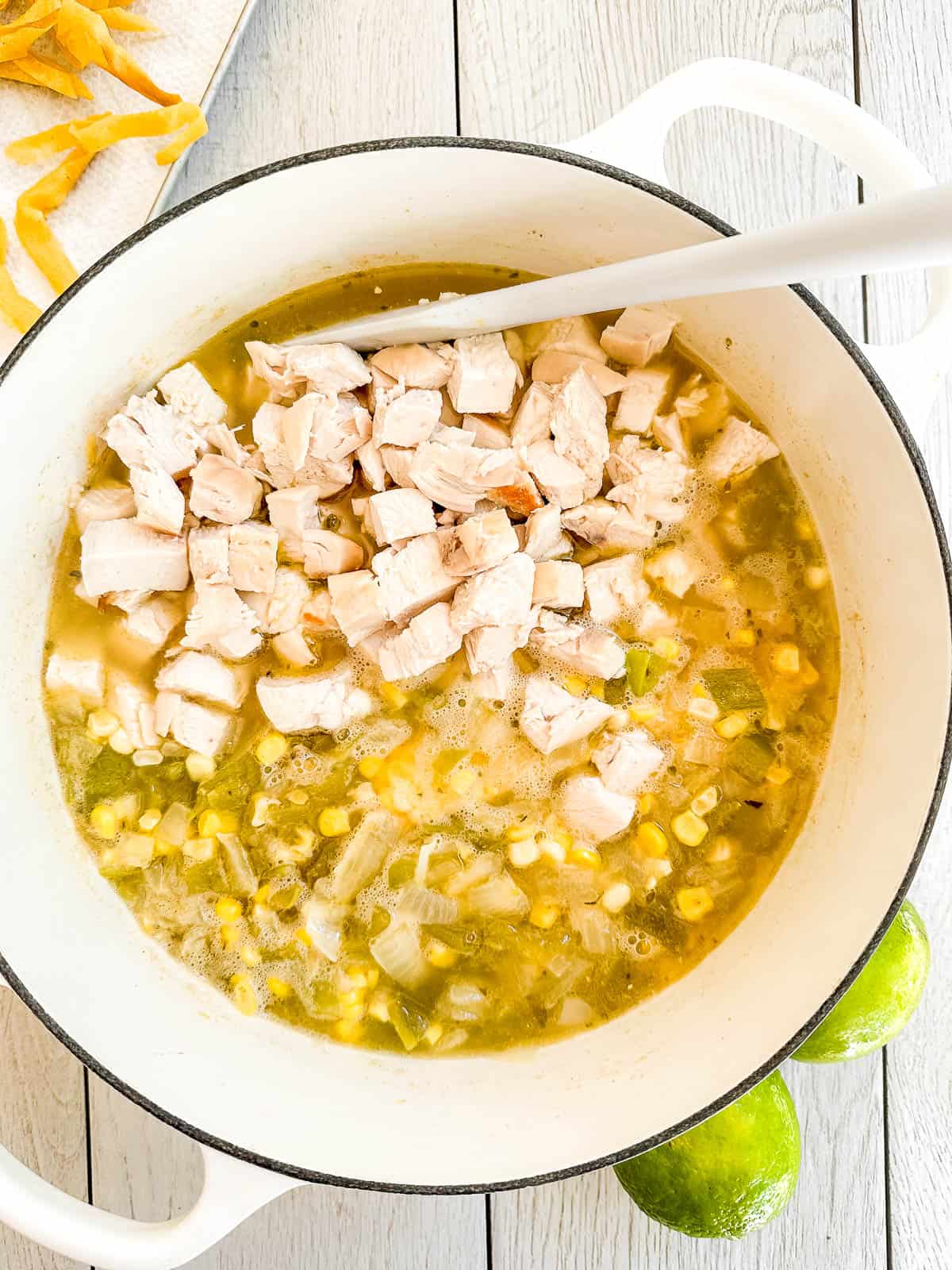 Adding chicken to white chicken chili.