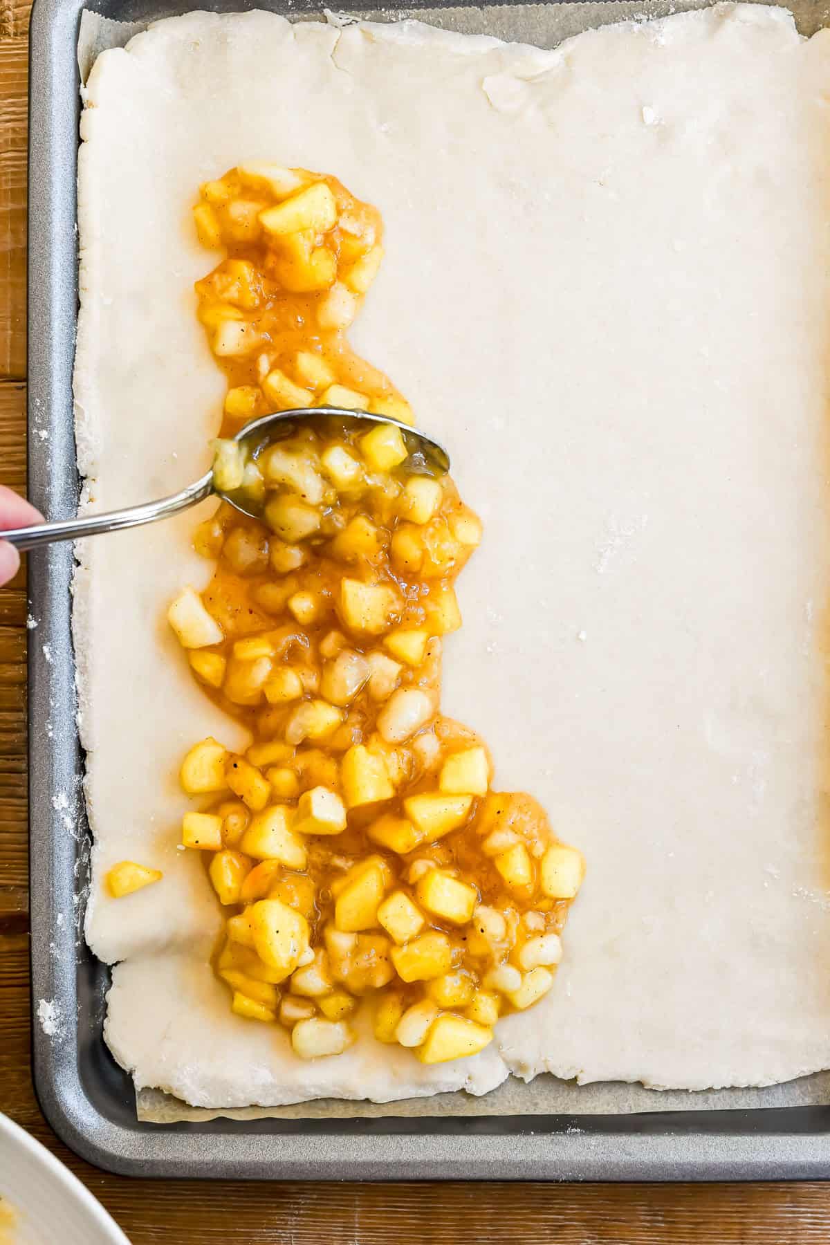 adding apple pie filling to the pastry for apple pie bars.