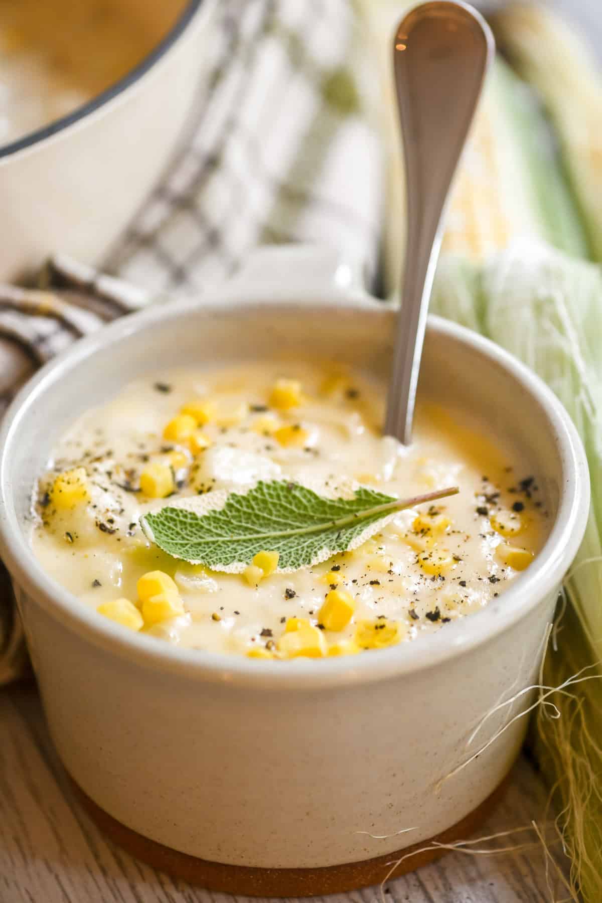 a mug of corn and cheddar cheese soup with spoon.