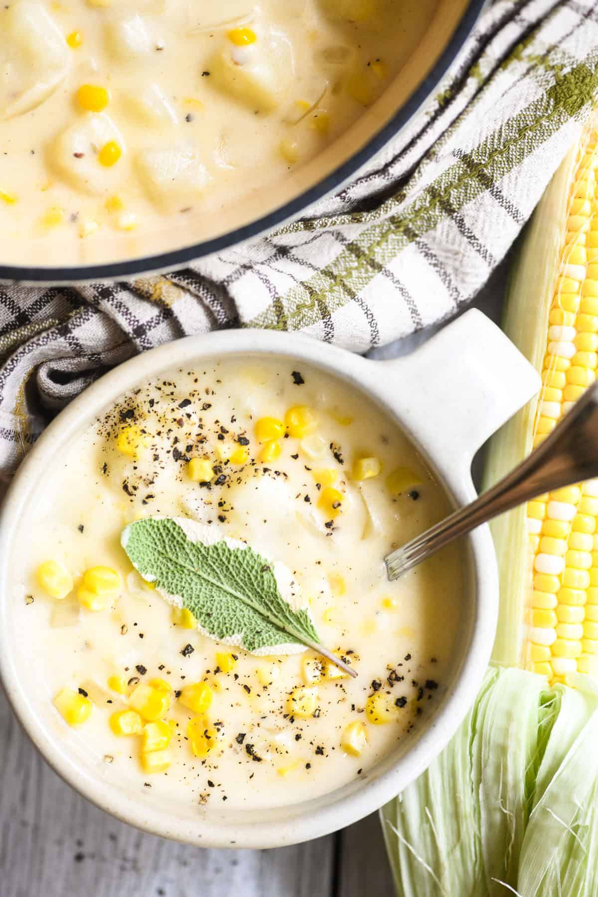 a mug of corn and cheddar cheese chowder with fresh corn.