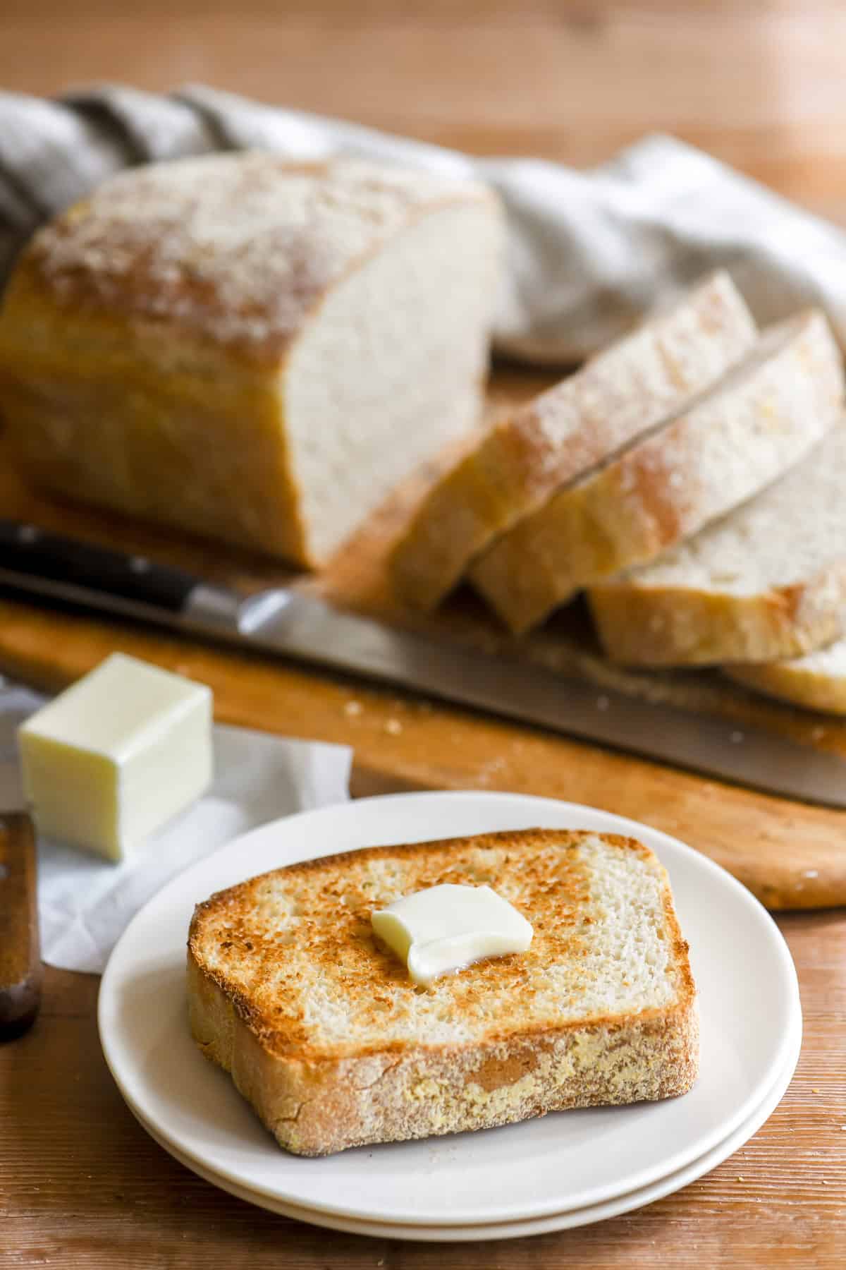 a slice of toasting white bread on a plate with melting butter.