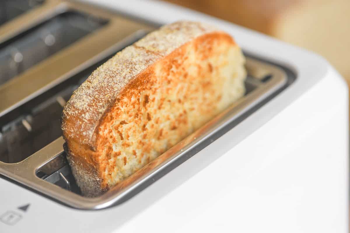 A slice of Toasting White Bread in a toaster slot.
