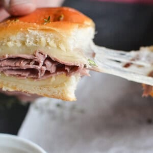 pulling apart a French dip slider with gooey melted cheese.
