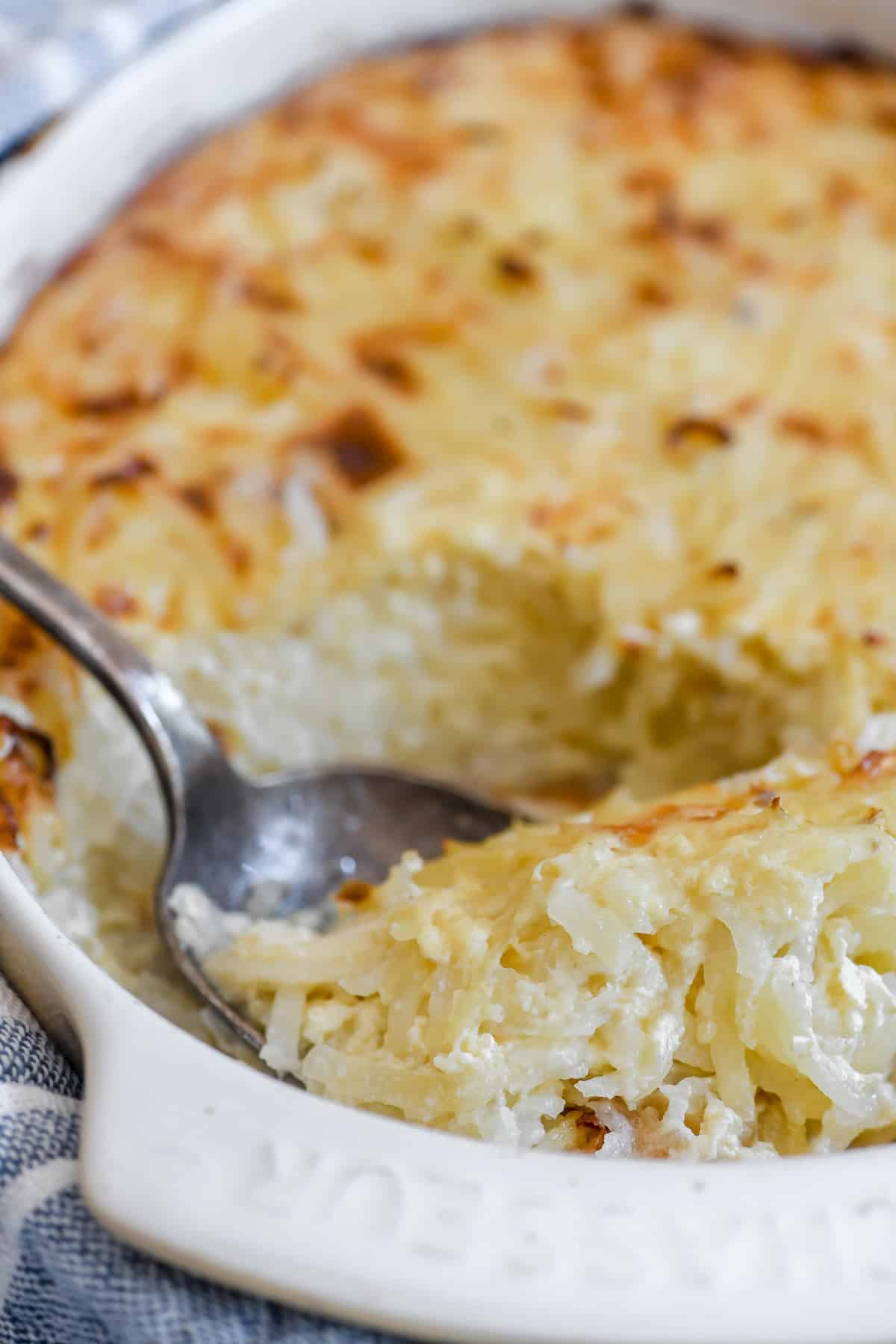 Serving grated potato casserole with a large spoon.