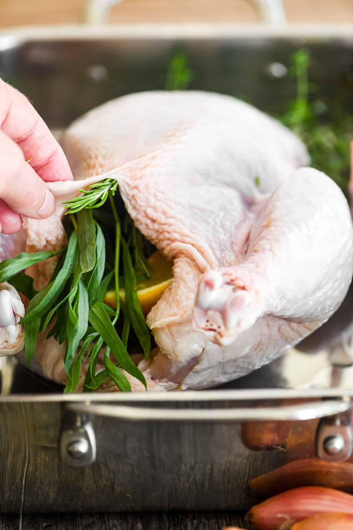 Stuffing a roast chicken with lemon wedges, garlic, and herbs.
