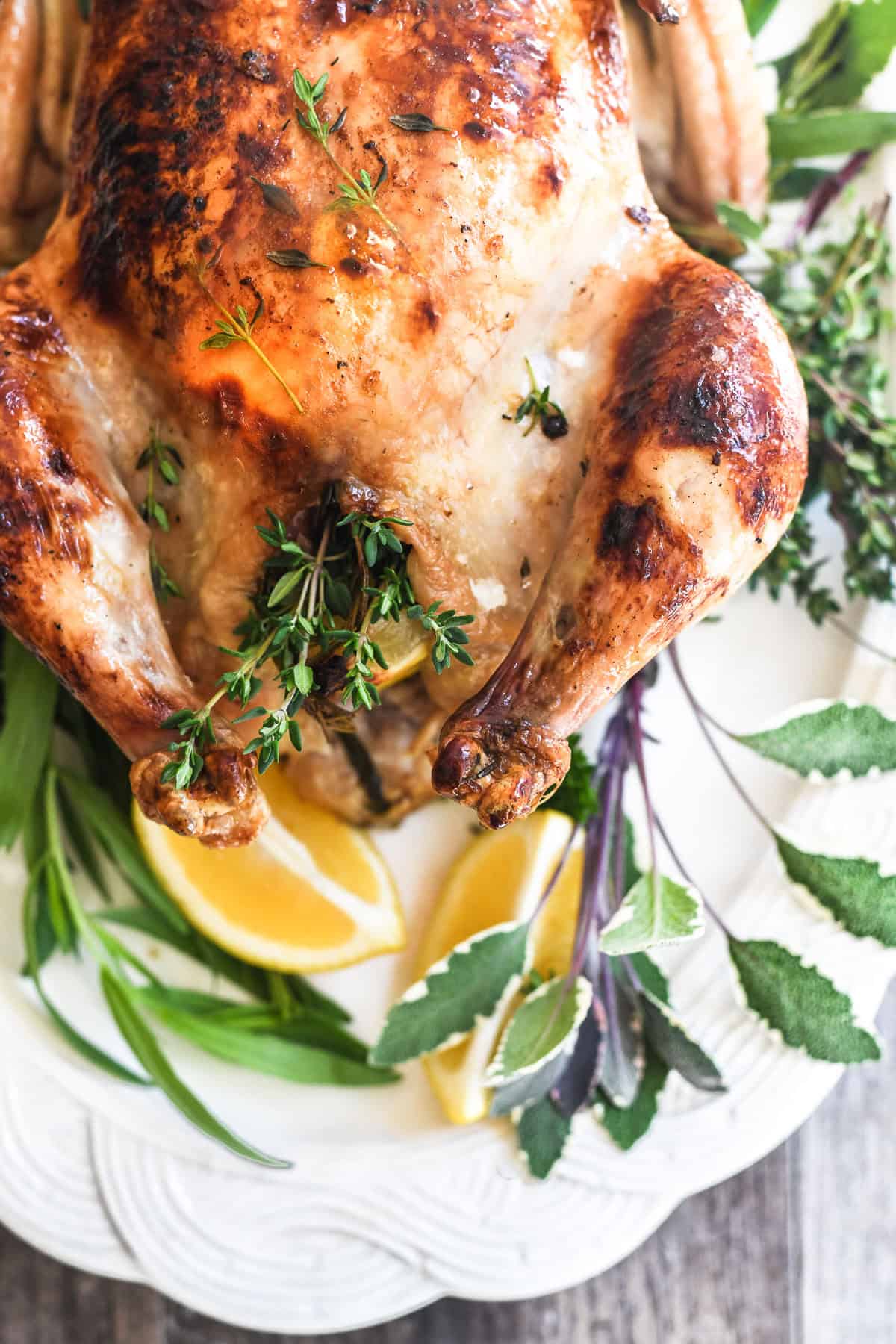 Roast chicken with lemon and herbs on a platter.