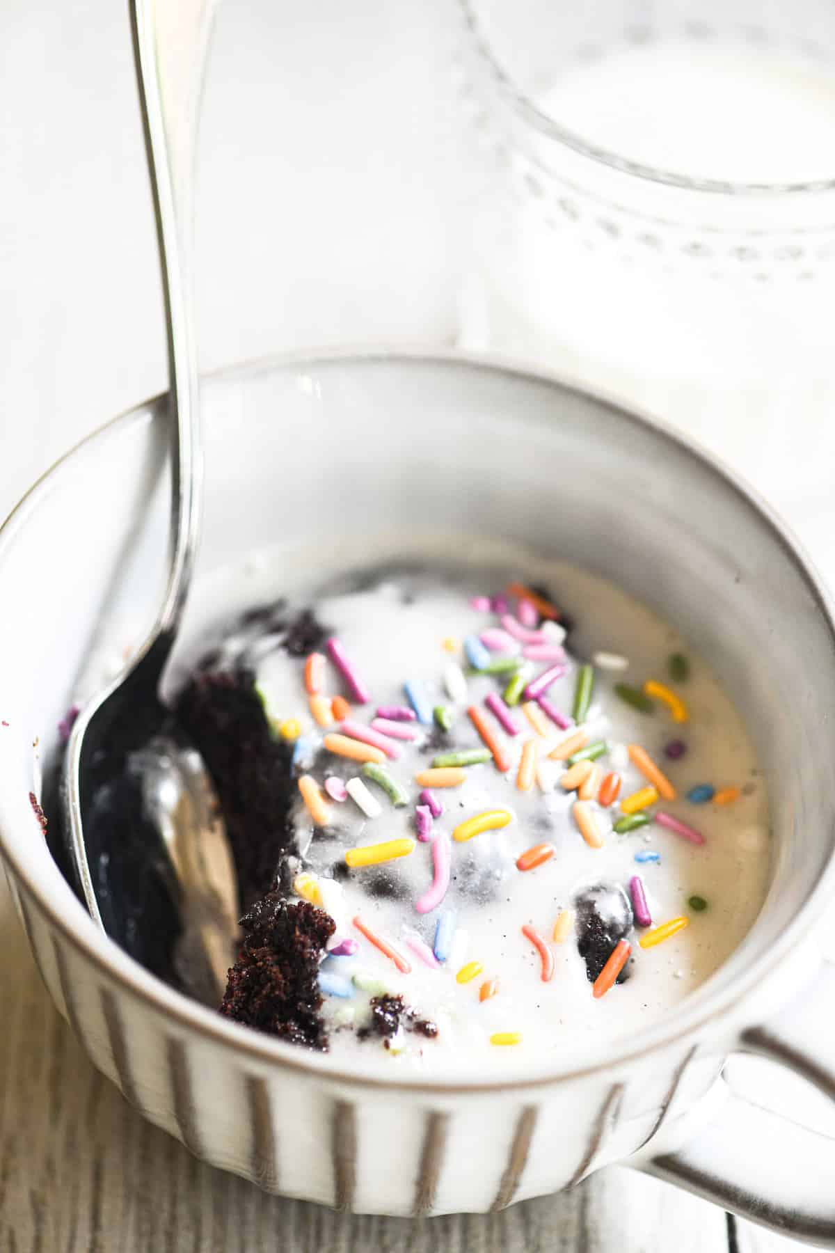 one minute microwave mug cake with frosting and sprinkles.