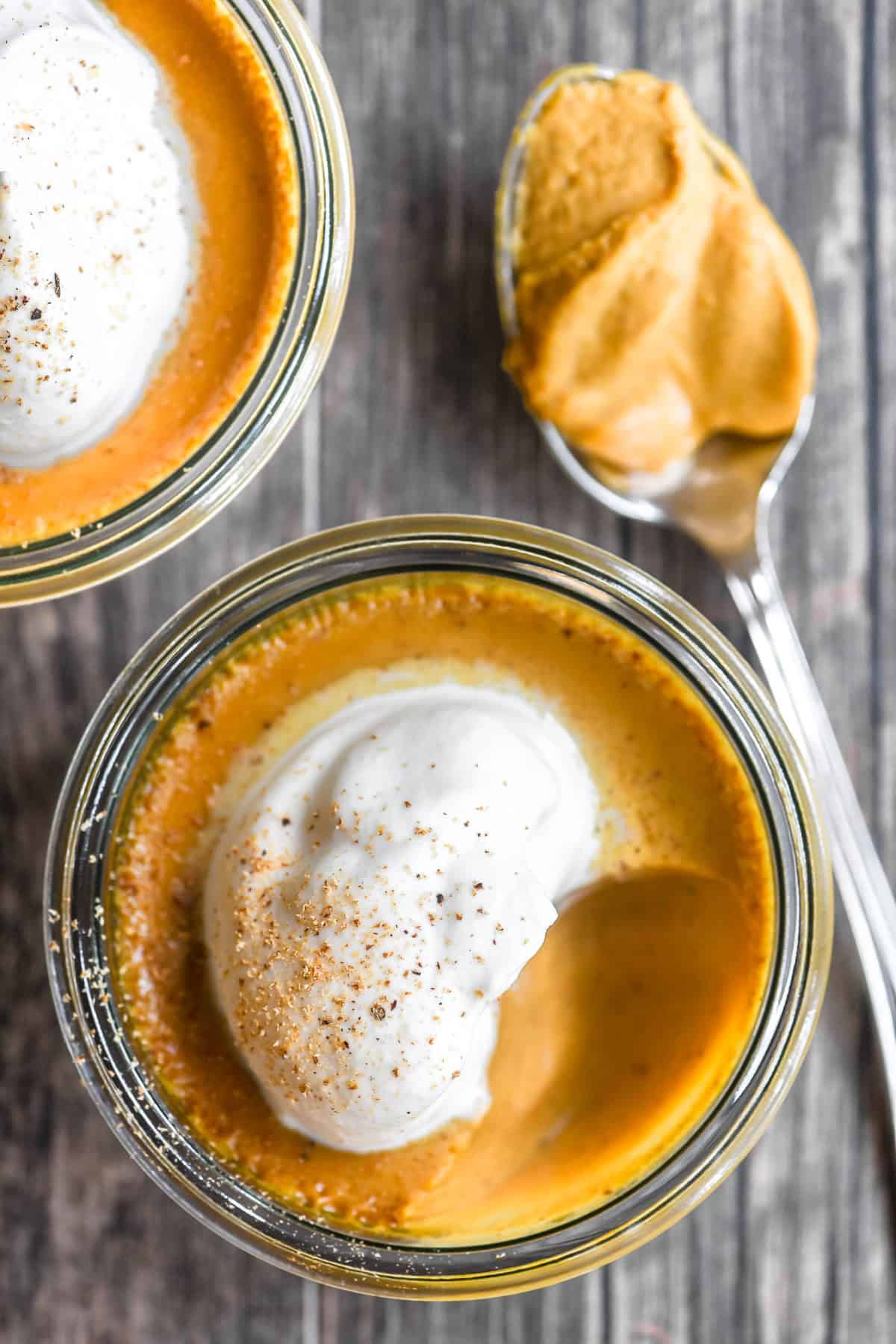 pumpkin pot de creme in a small jar with whipped cream and grated nutmeg.