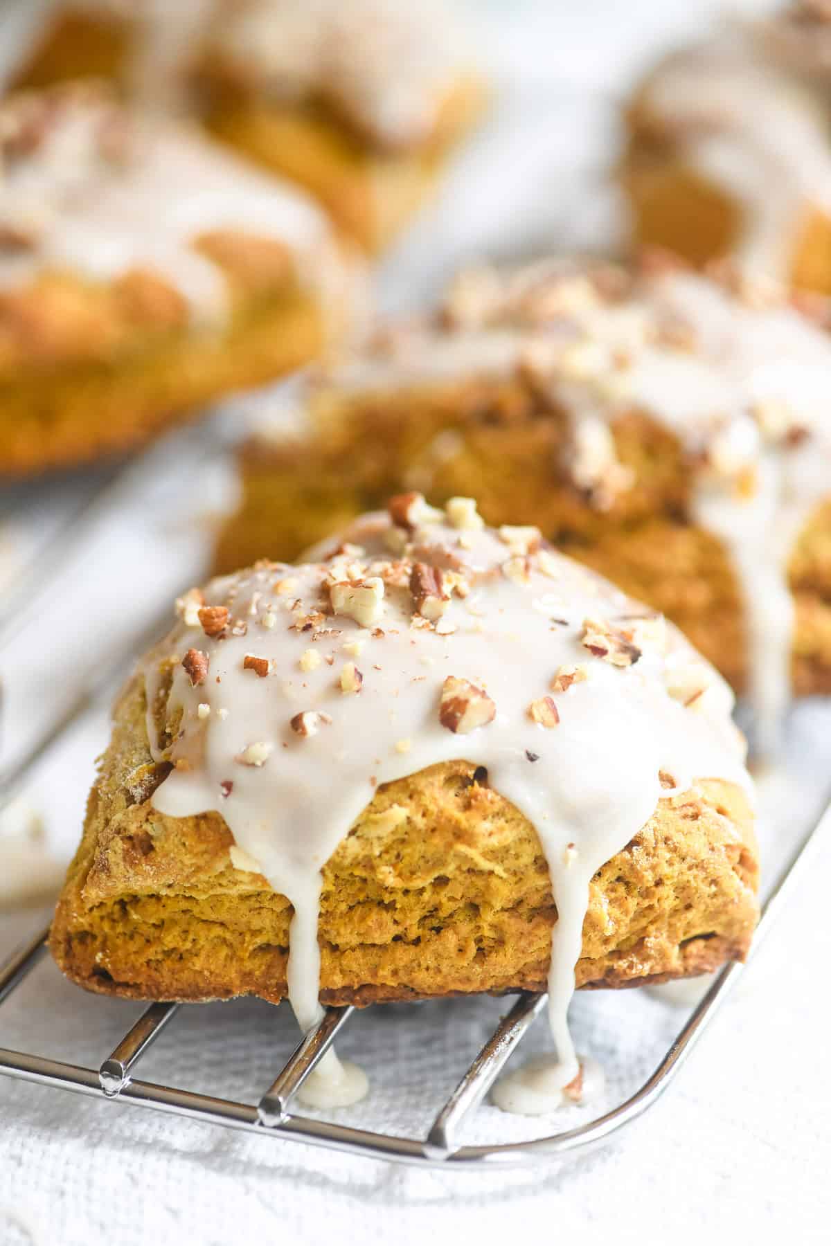 glazed pumpkin scones with crushed pecans, on a rack.