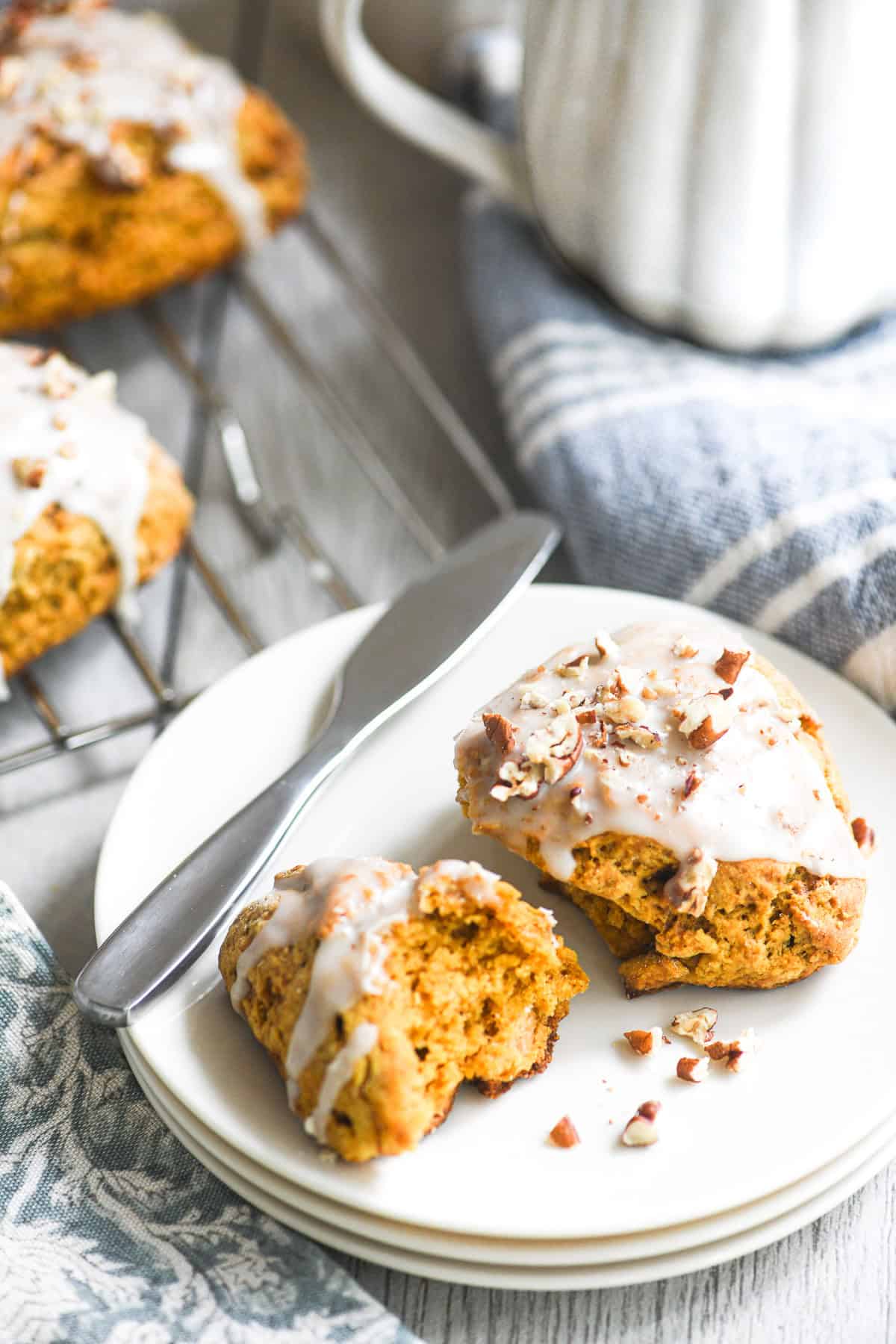 glazed pumpkin scone on a plate with coffee mugs.