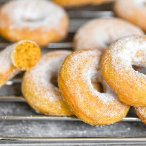baked pumpkin spice doughnuts coated in sugar, on a baking rack.