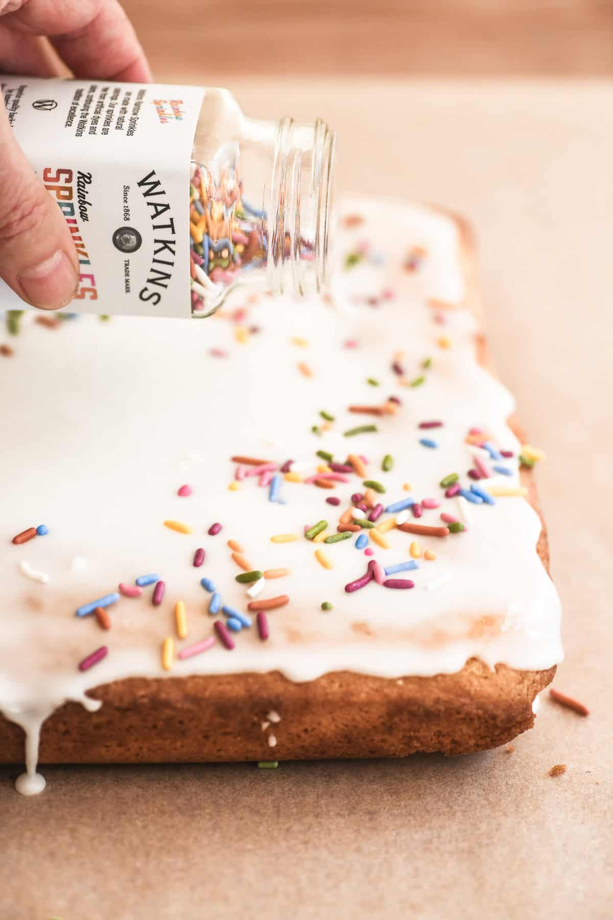 Adding sprinkles to an iced school cake.