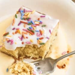 taking a bite of school cake with sprinkles, on top of custard.