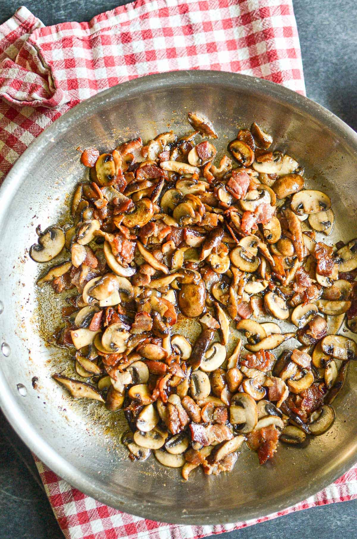 Sauteed bacon and mushrooms in a skillet.