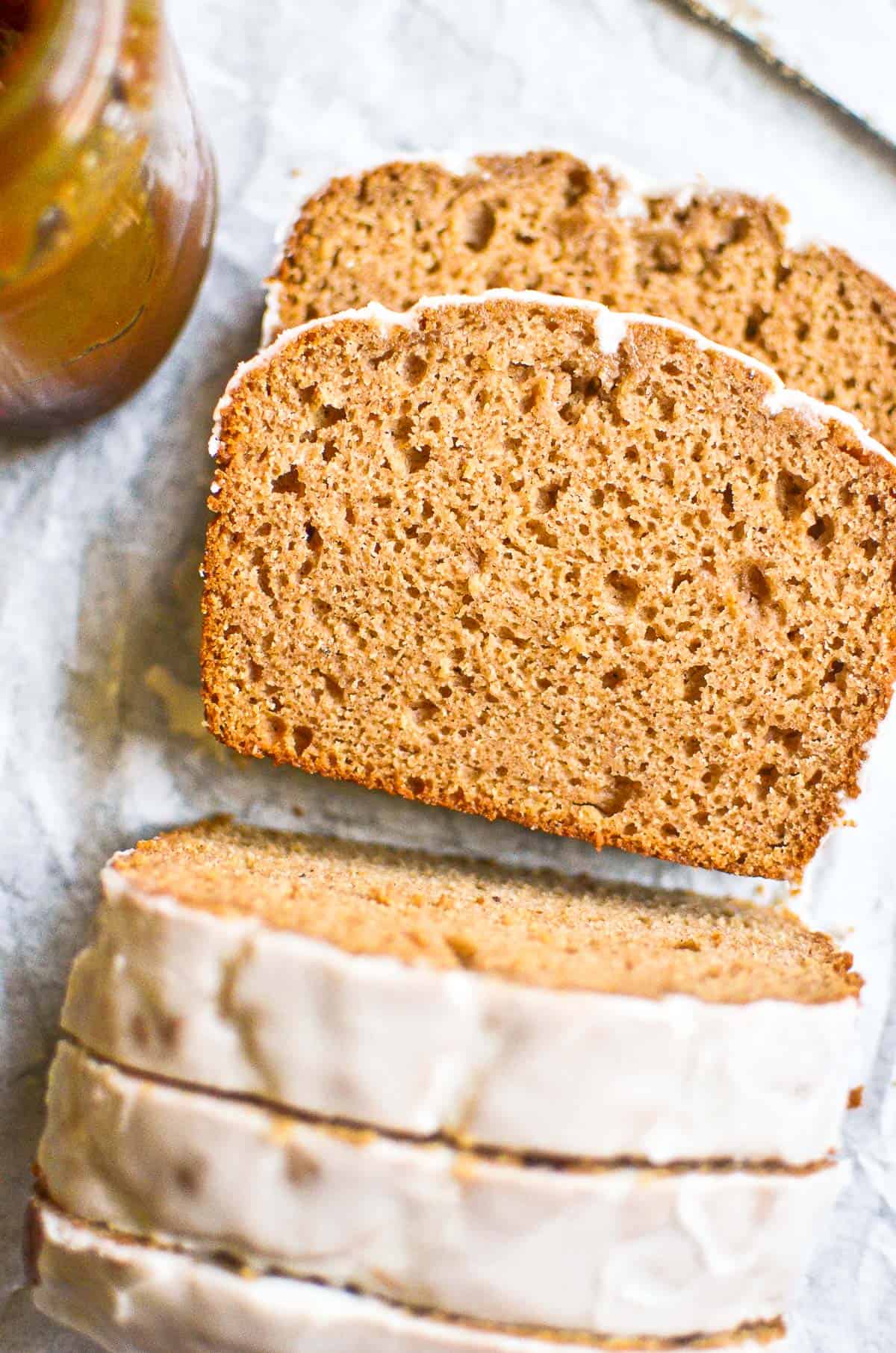 Spiced apple cake with vanilla glaze, on a piece of parchment paper.